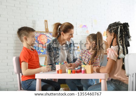 Children with female teacher at painting lesson indoors