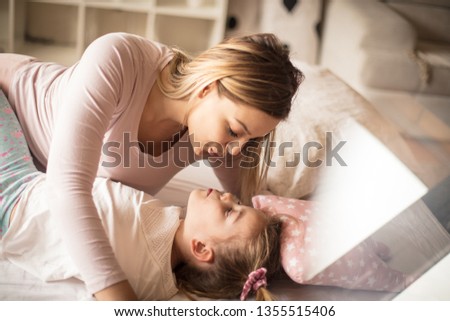 One kiss for my little girl. Mother daughter playing in bed.