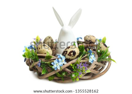 Decorative easter rabbit sitting in beautiful nest with quail eggs isolated on white. Concept holiday Easter.