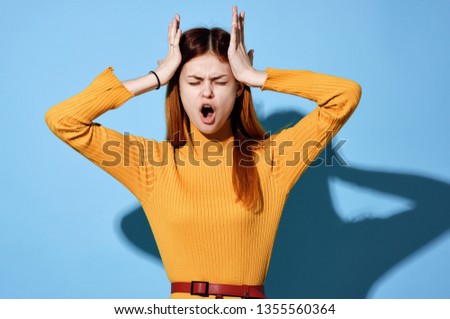 Woman pain in temples yellow sweater blue background                             