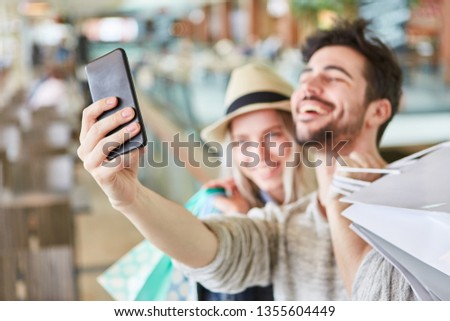 Young couple is taking a selfie with their smartphone while shopping