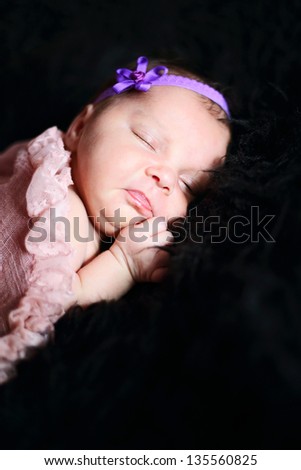 A sleeping newborn baby on dark background