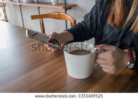 Close-up of woman's hands holding cell phone while drinking coffee in modern cafe. surfing the web / internet in smartphone. Coffee break business.