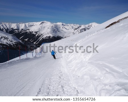 Skier on the slope and peaks of the mountains in the background