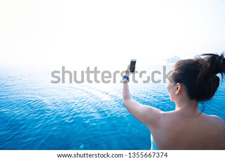 Asian woman using smartphone at swimming pool. Summer holiday concept