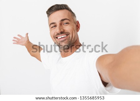 Image closeup of european man 30s wearing casual t-shirt looking on camera while taking selfie photo isolated over white background