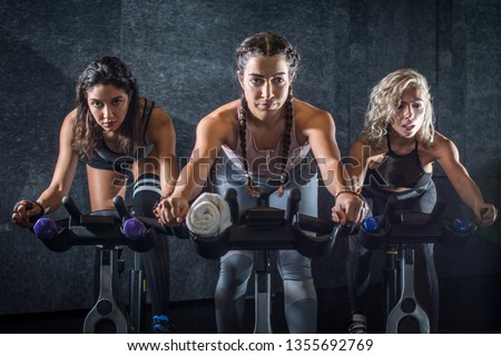 Group of young sporty women riding cycling bikes during spinning class indoors Royalty-Free Stock Photo #1355692769