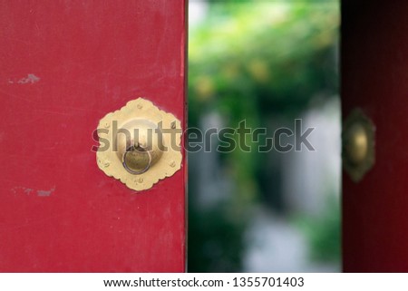 
Red and gold door in Beijing with green and natural blurred bokeh in the background
