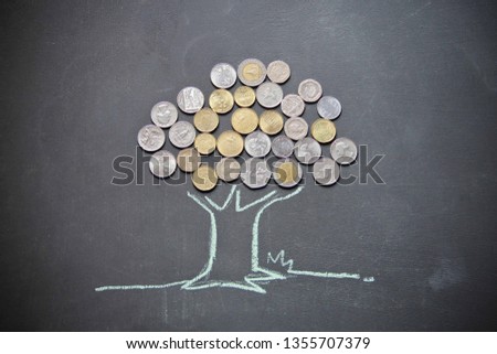 Drawing of a tree with different countries’ currency are with chalk on blackboard. This photo shows economical concept. 