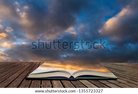 Beautiful colorful golden hour sunset sky with cloud formation and setting sun in pages of open book, story telling concept