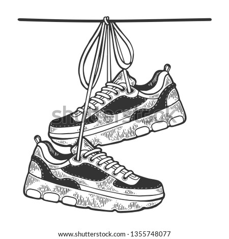 Sneakers are hanging on wire sketch engraving vector illustration. Scratch board style imitation. Black and white hand drawn image.