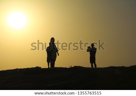 Photographer taking photos of a wife and a child on desert at sunset.