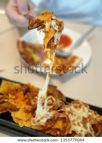 The picture was intended to focus on the strechy nacho cheese on the spoon with a blurred background dish. The crispy nachos lies under the delightful baked mozzarella cheese.