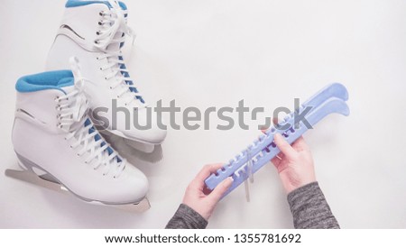 Flat lay. Putting on blue blade guards on white figure skates.