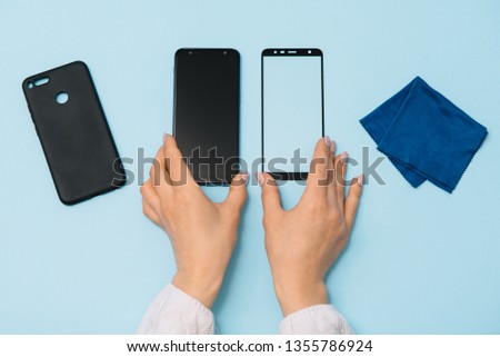 Smartphone with screen protect glass cover in hands. blue background. women hand stick tempered glass shield or film screen cover with mobile phone. protector concepts ideas