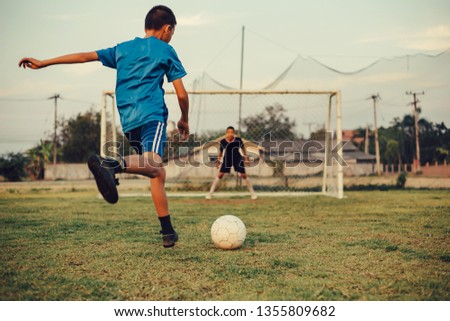 An action sport picture of a group of kids playing soccer football for exercise in the green grass field.