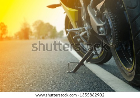 A motorcycle parking on the road right side and sunset.