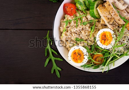 Fresh salad. Breakfast bowl with oatmeal, chicken fillet, tomato, lettuce, microgreens and boiled egg. Healthy food. Vegetarian buddha bowl. Top view