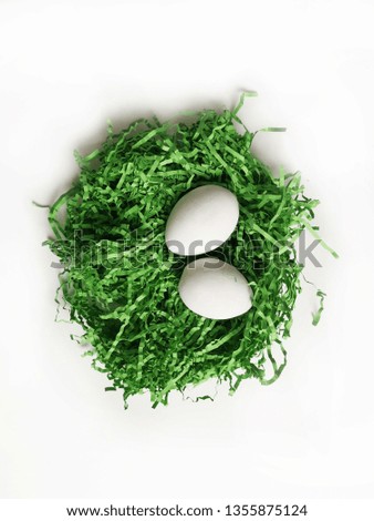 Two white Easter eggs on green artificial grass. Top view of the white table with still life