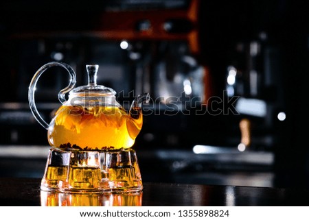 buckthorn tea in a glass teapot and cups, glass teapot with fruit hot tea in a cafe with orange, place for logo design copyspace