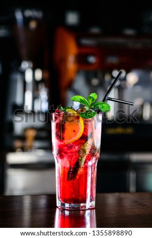 Raspberry pink Mojito Lemonade with lime and fresh mint in glass on bar counter in a nightclub. Summer refreshing cocktail. Copy space on bar blurred background