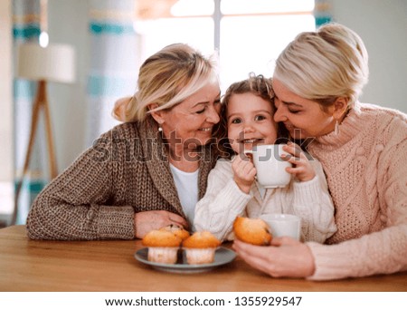 A portrait of small girl with mother and grandmother at the table at home. Royalty-Free Stock Photo #1355929547