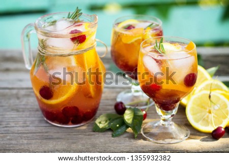 Homemade refreshing drink. Wine sangria or punch with fruits in glasses, cocktails with fresh fruits, berries and rosemary on a wooden rustic table. 
