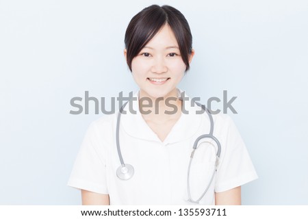 Young nurse with stethoscope against pale blue background