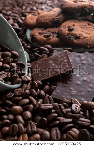 on coffee beans the cup lies, opposite a chocolate bar, there are cookies behind