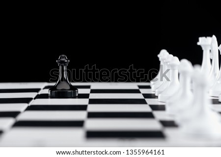 selective focus of chessboard with white chess figures and black pawn in front isolated on black