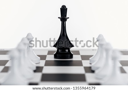 selective focus of chessboard with black queen figure among white pawns isolated on white