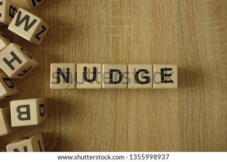Nudge word from wooden blocks on desk Royalty-Free Stock Photo #1355998937