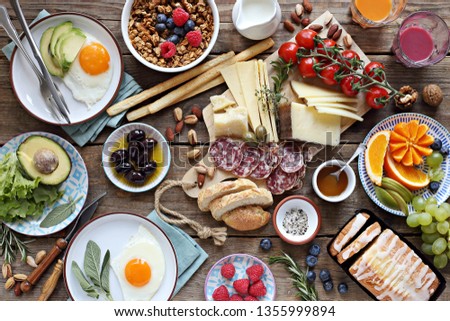  Brunch or breakfast set, meal variety with fried eggs, sausage and cheese variety, granola, smoothie, fruits and berries. Overhead view