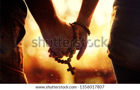 Couple praying together. Holding rosary in hand. Royalty-Free Stock Photo #1356017807