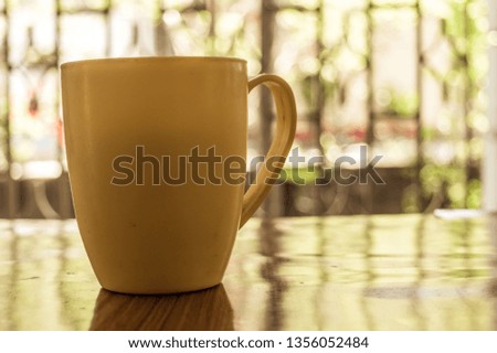 Closeup image of a cup of Cappuccino, mocha, latte, Americana, espresso hot coffee aroma for on rustic wooden table background in cafe with backdrop of sunlight light coming from window in morning.