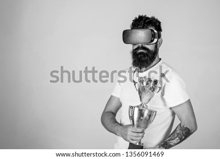 Man with nerdy beard in VR headset isolated on gray background. Bearded man holding 1st prize. Hipster with trendy beard and mustache won contest. Champion of online games tournament, gaming concept.