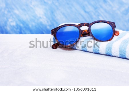Sunglasses and cotton towel on sand beach with copy space.  Summer background.