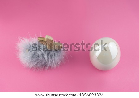 Easter bunny with fluffy feathers and big white easter egg.

Modern decoration elements for easter in front of pink background. From above


