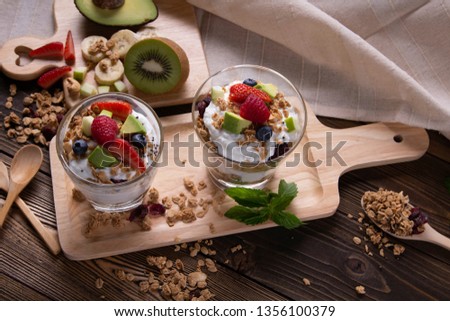 Closeup of Healthy layered dessert with yogurt, strawberry, jam, blackberry in glass on wooden background