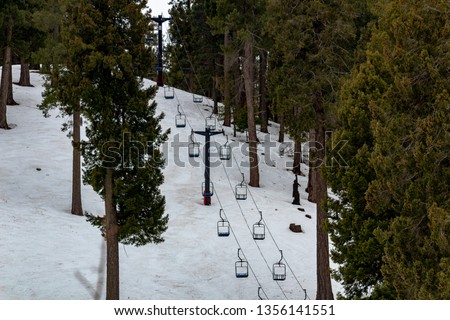 Chair lifts at Mount Lemmon Ski Valley in the Catalina Mountains. Snow covers the ground with pine trees dotting the side of the mountain. Pima County, Tucson, Arizona. March of 2019.