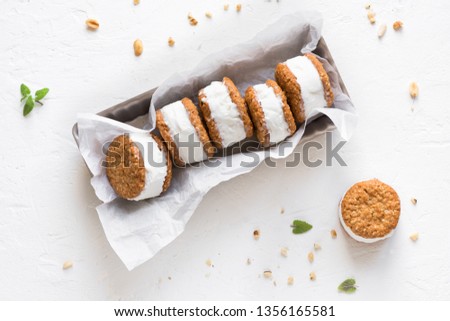 Ice cream sandwiches with nuts and wholegrain cookies. Homemade vanilla ice cream sandwiches on white background, top view.