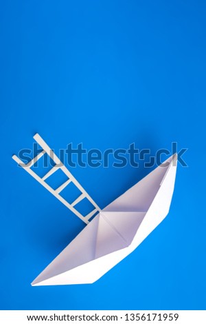 White paper boat with a white ladder on a blue background. The concept of travel, leisure, career. Space for text.