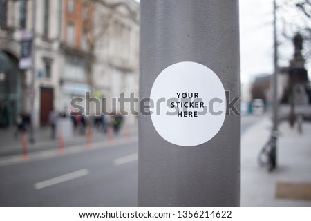Sticker Mockup on a street lamp in a busy city street Royalty-Free Stock Photo #1356214622
