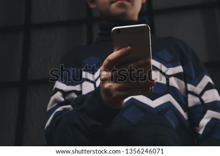 Teen boy holding phone and feeling sad. Victim of cyberbullying. Phone bullying. Royalty-Free Stock Photo #1356246071