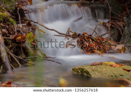Wet stone near a waterfall during the autumn, blured water, long time exposure