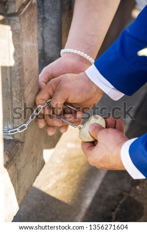 A couple holding a lock of heart on a bridge on their wedding day tradition