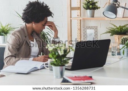 Serious african-american business woman working on laptop at office