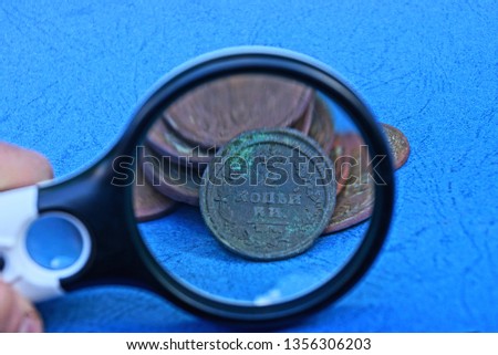 magnifier and a bunch of old copper coins on a blue table