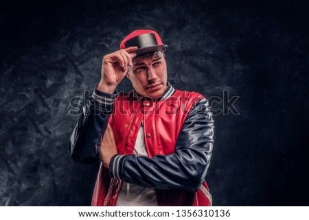 Close-up portrait of a handsome man dressed in a hip-hop style. Studio photo against a dark textured wall