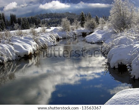 Sunny Riverbank after a snowstorm with reflecting water